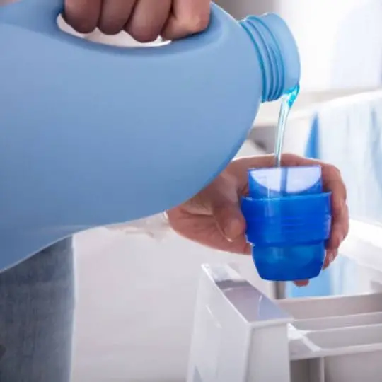 human pouring laundry detergent on cup