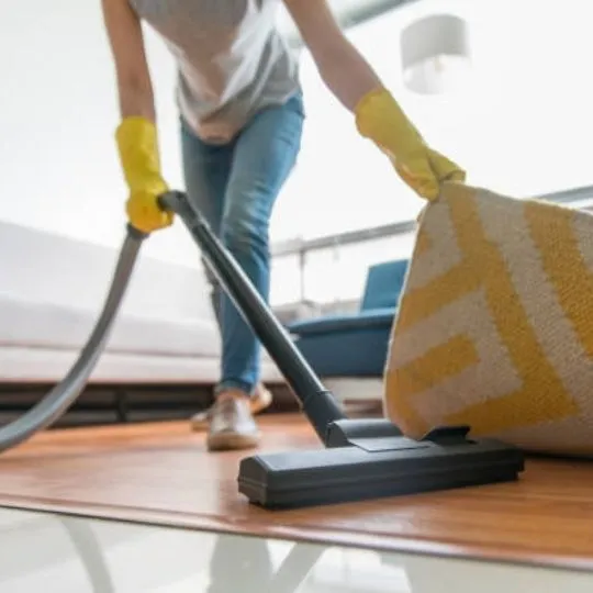 human vacuuming the underside of a carpet
