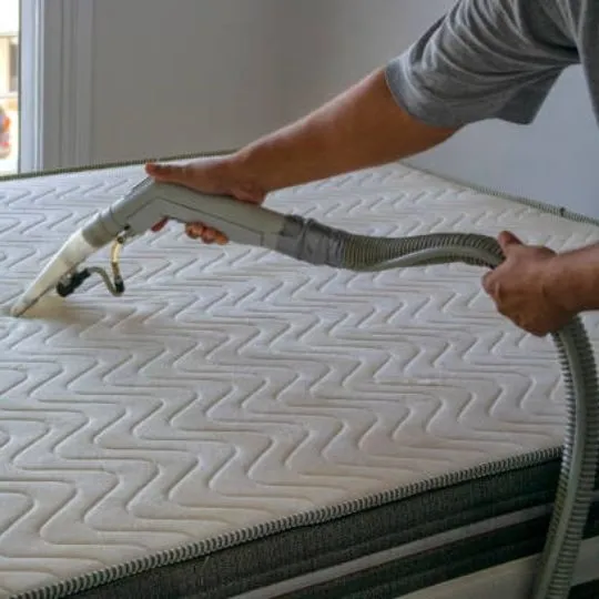 human vacuuming a mattress
