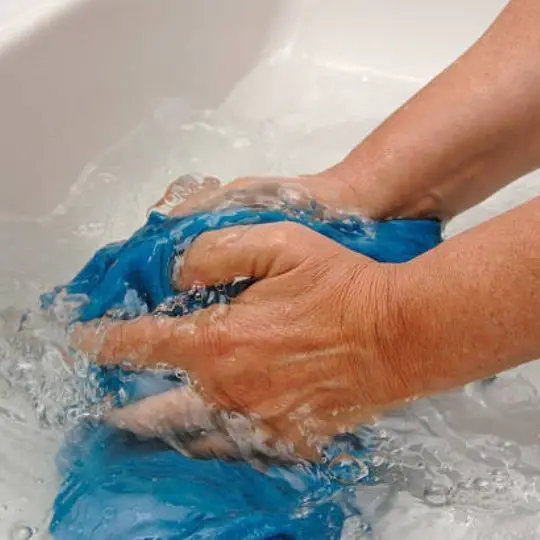 human washing a piece of clothing in water