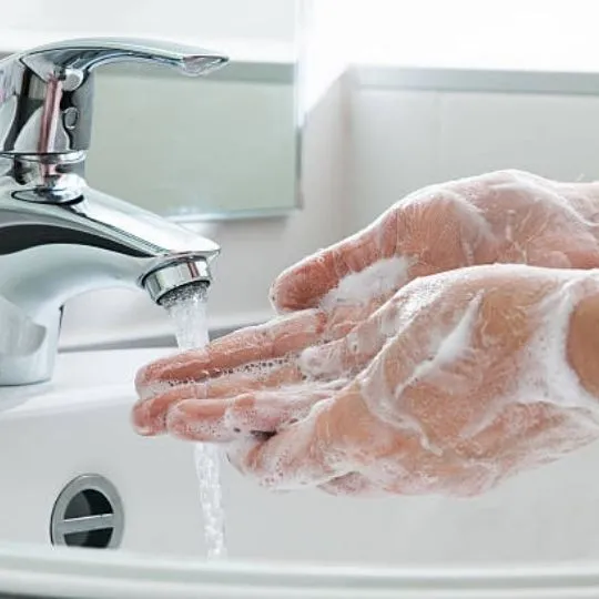 human washing hands with soap on sink