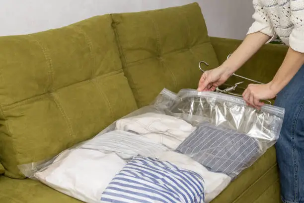 Woman using vacuum storage bags to keeping apparel at home.Empty space