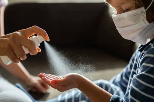 rubbing alcohol being sprayed on boy's hand