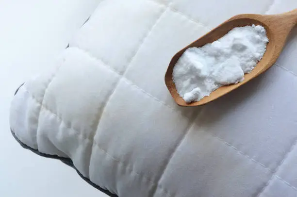 White pillow with stains and baking soda (sodium bicarbonate) on white background. baking soda to clean their dirty mattresses and Home cleaning concept.