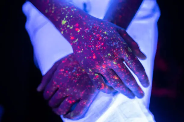 A close up of crossed hands under UV lights